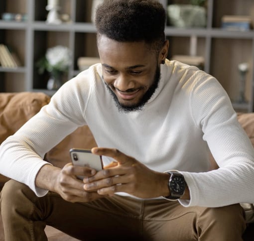 A young man sitting in a living room video calling using a smart phone