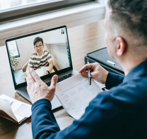 A busninessman using a laptop to video call with his young son