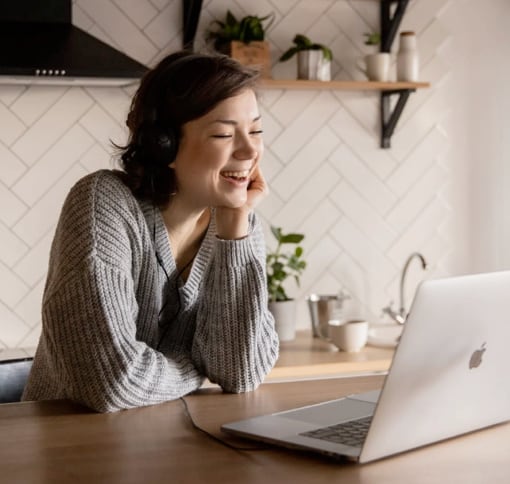 Woman using laptop for video call while sitting in kitchen